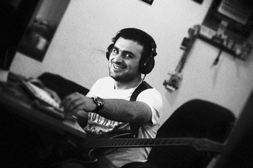 Tigran Arakelyan in the studio, wearing headphones with a guitar